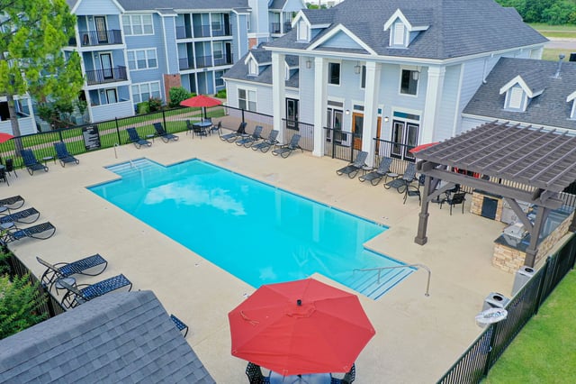 Aerial view of a resort-style swimming pool with lounge chairs and an outdoor kitchen area at a multifamily property.
