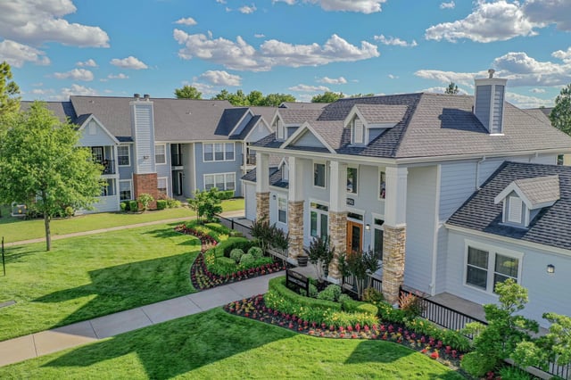 Exterior view of apartment buildings with manicured lawns and flower beds.
