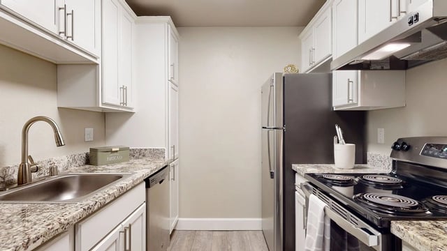 Modern kitchen with granite countertops, stainless steel appliances, and white cabinetry.