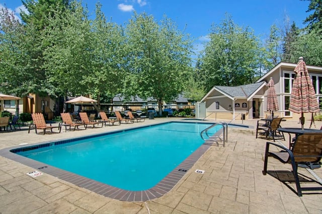 Outdoor swimming pool with lounge chairs and umbrellas.