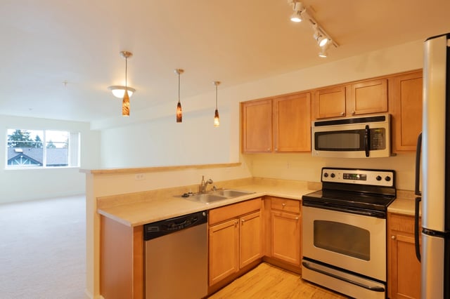 Modern kitchen with stainless steel appliances, wood cabinets, and a breakfast bar.
