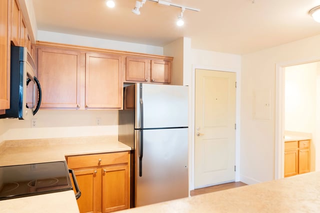 Kitchen with wood cabinets, stainless steel refrigerator, microwave, and stovetop.