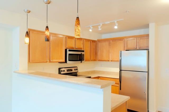 Modern kitchen with stainless steel appliances and light wood cabinets.