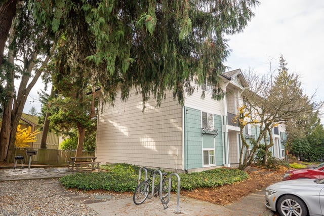 Apartment building exterior with trees and outdoor grills.