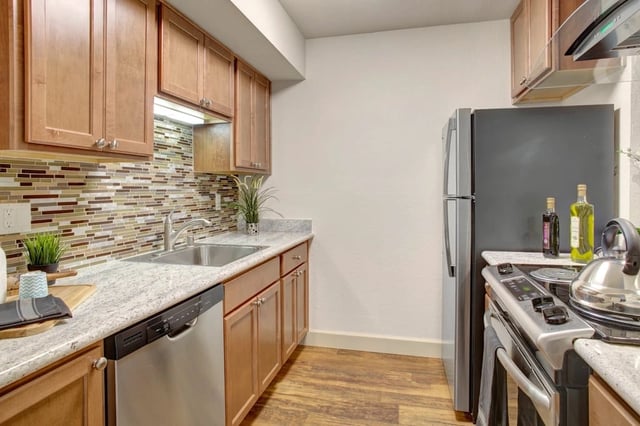Modern kitchen with stainless steel appliances, granite countertops, and wood cabinets.