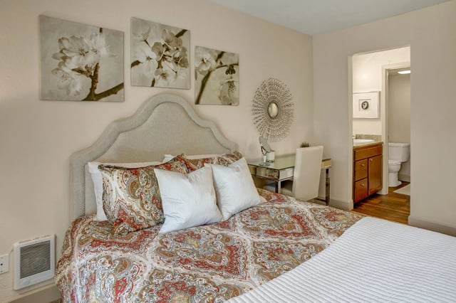 Bedroom with a queen-size bed, vanity, and doorway to bathroom
