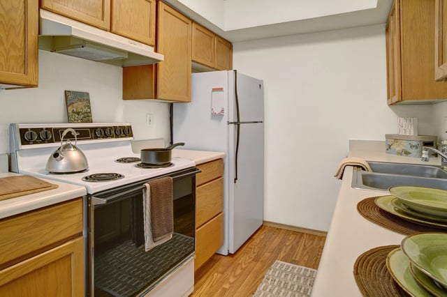 Kitchen with wood cabinets, white refrigerator, and stainless steel sink.