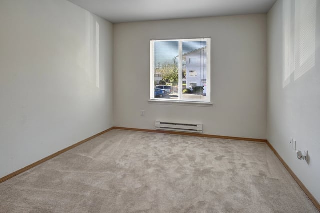Empty bedroom with beige carpet and blinds on the window