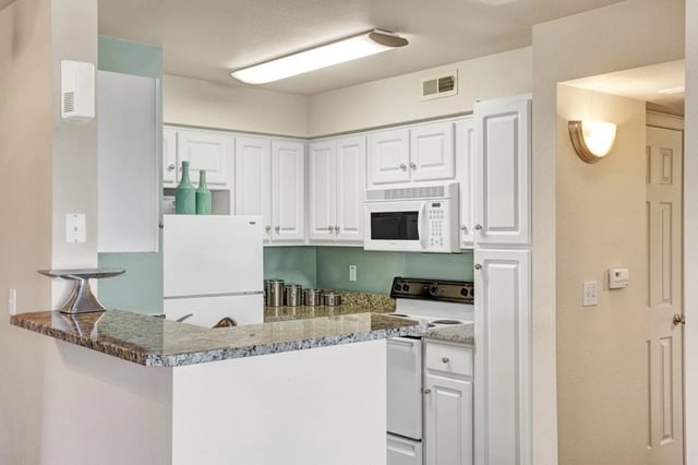 Kitchen with white cabinets, granite countertops, and a breakfast bar.