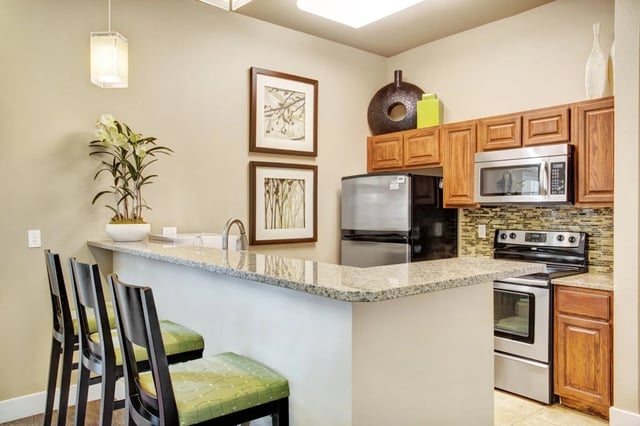 Modern kitchen with granite countertops, stainless steel appliances, and bar seating.