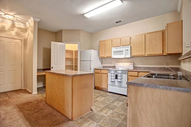 Kitchen with light wood cabinets, white appliances, and an island.