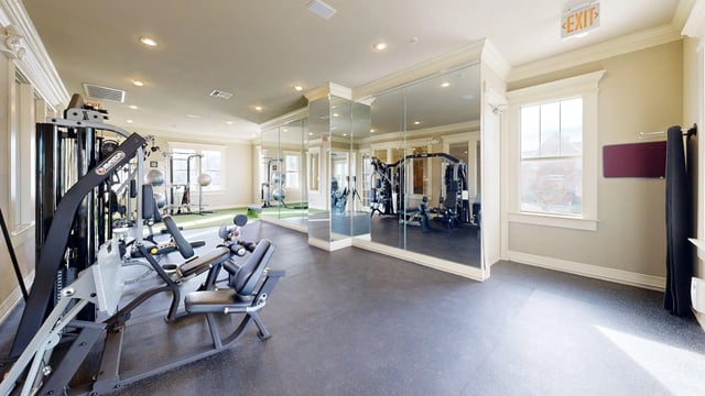 Gym with weight machines, free weights, and mirrored walls.
