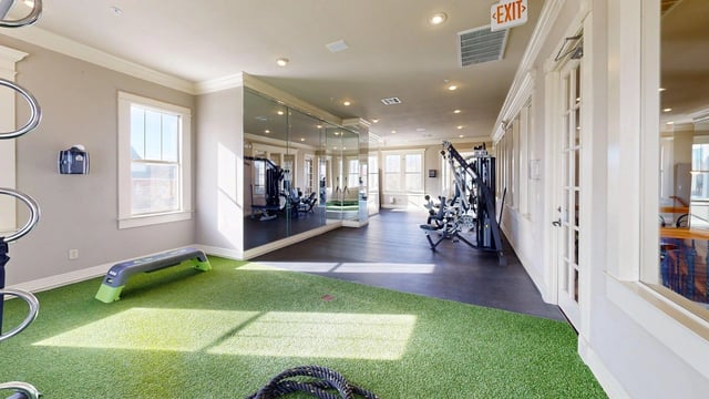 Interior of a gym with cardio machines, weight machines, and turf flooring.