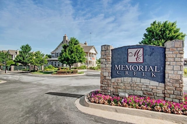 Memorial Creek apartment complex monument sign with buildings in background.