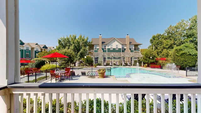 Apartment complex pool area with lounge chairs and umbrellas.