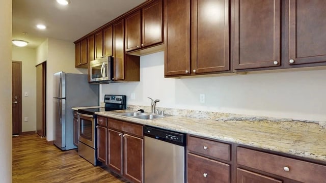 Kitchen with stainless steel appliances, granite countertops, and dark wood cabinets.