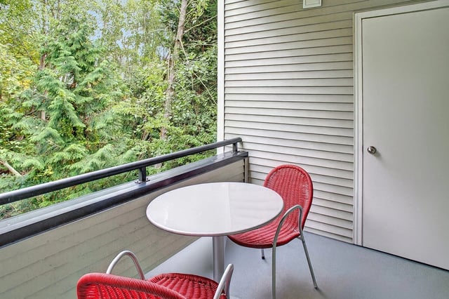 Balcony with seating area overlooking trees.