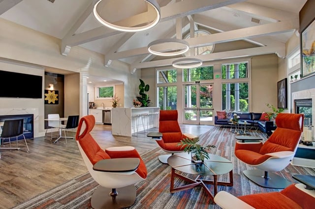 Modern seating area with unique chairs and a bar in a community lounge.