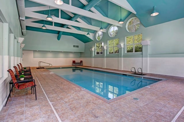 Indoor swimming pool with lounge chairs and tables.