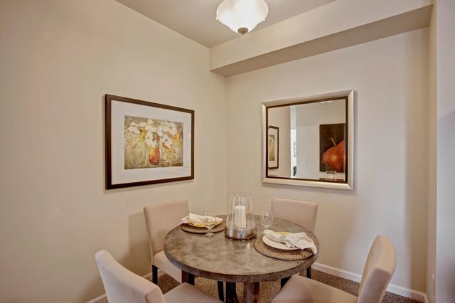 Dining area with a round table, four chairs, and artwork on the wall.