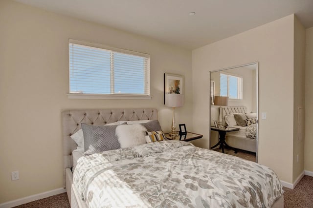 Bedroom with a queen-sized bed, nightstand, and mirrored closet.