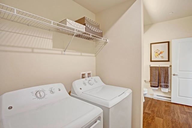 Washer and dryer in laundry room with shelving and decorative items.