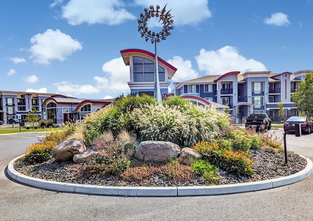 Apartment building exterior with landscaping and a unique metal sculpture.