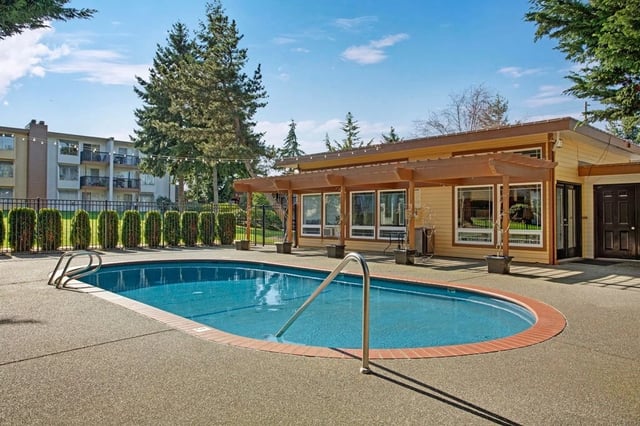 Outdoor swimming pool with lounge area and building in the background