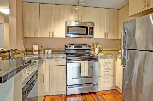Kitchen with stainless steel appliances, granite countertops, and light wood cabinets.