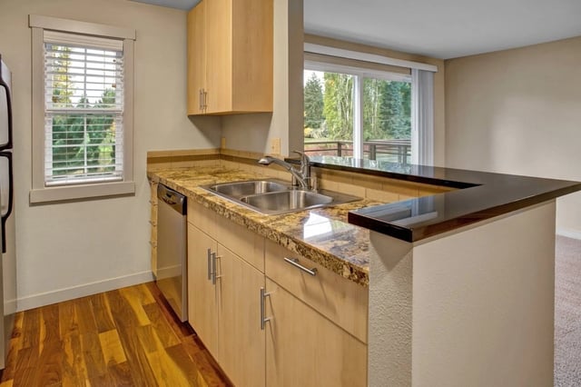 Modern kitchen with light wood cabinets, granite countertops, and stainless steel appliances.