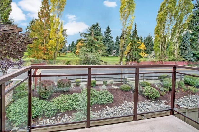 View from balcony overlooking a landscaped area with trees and a road.