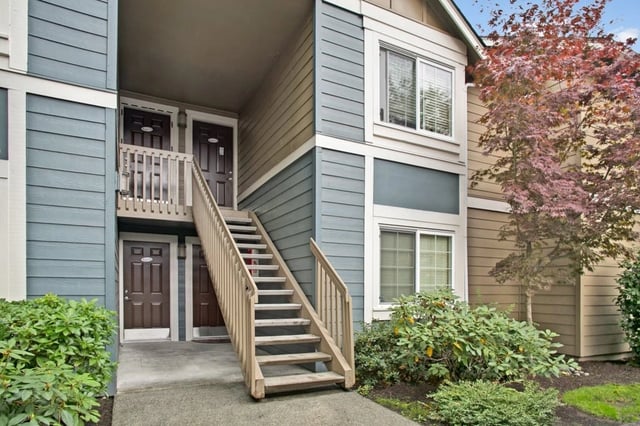 Exterior view of apartment building with stairs and entrances.