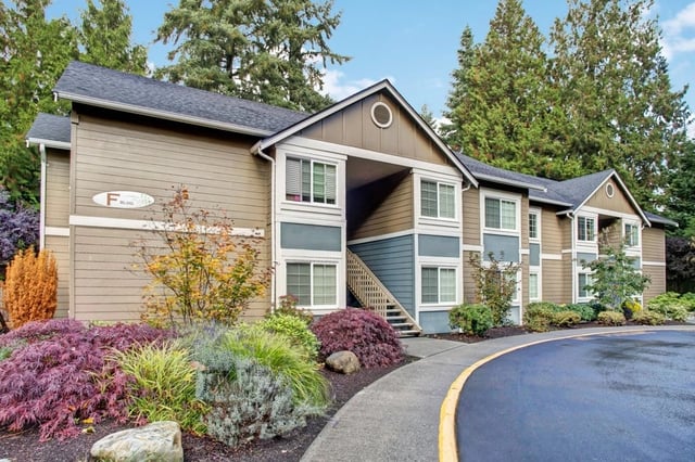 Exterior view of an apartment building with landscaping and pathway.