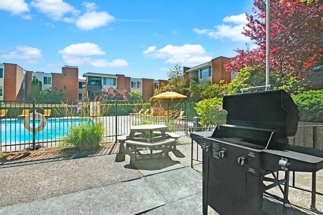 Outdoor swimming pool area with picnic table and barbecue grill.