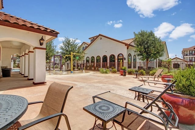 Outdoor splash pad and lounge area with lounge chairs and tables.