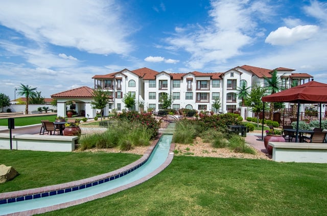 Exterior view of a multifamily building with a water feature and outdoor seating area.