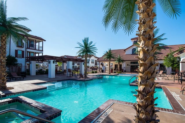 Resort-style swimming pool with lounge chairs and palm trees.