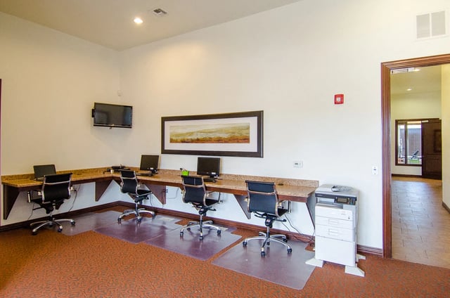 Business center with computers, printers, and chairs.
