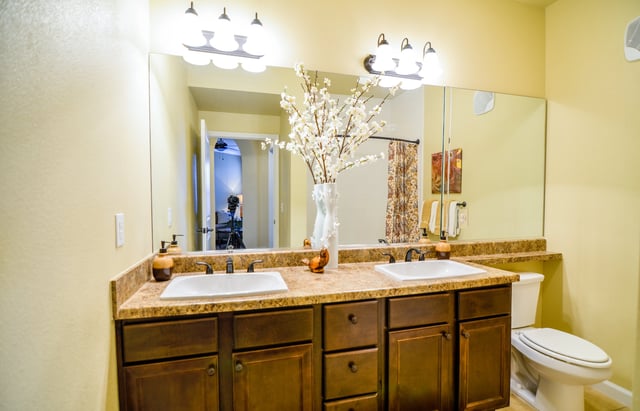 Double vanity with two sinks, dark wood cabinets, and a large mirror reflecting a doorway.