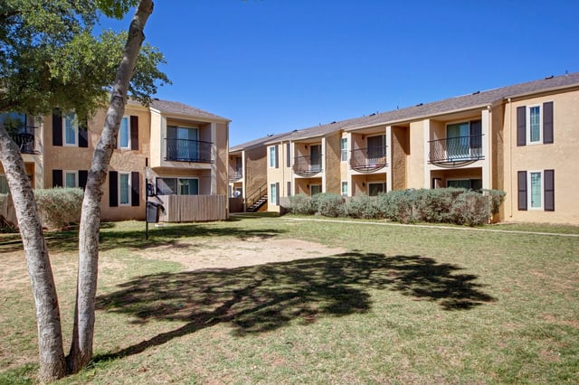 Apartment buildings exterior with balconies and green lawn in the foreground.