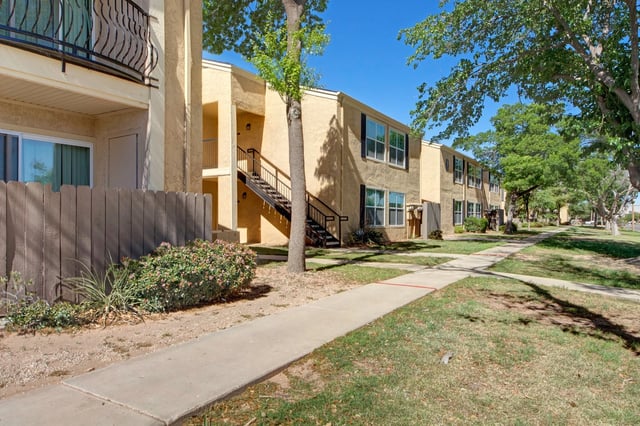 Exterior view of apartment buildings with walkways and trees.