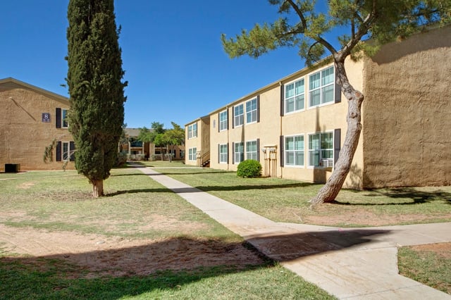 Exterior view of apartment buildings with walkways and trees.