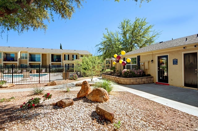 Apartment complex with a swimming pool, building entrances, and landscaping.