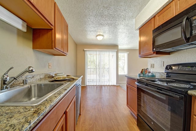 Kitchen with granite countertops, stainless steel sink, and wooden cabinets.