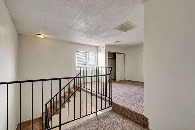 Interior view of a split-level apartment hallway with stairs and a closet.