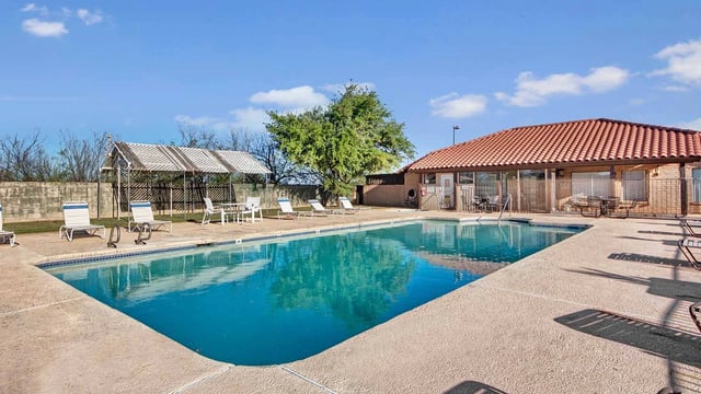 Community pool area with lounge chairs and a covered seating area.
