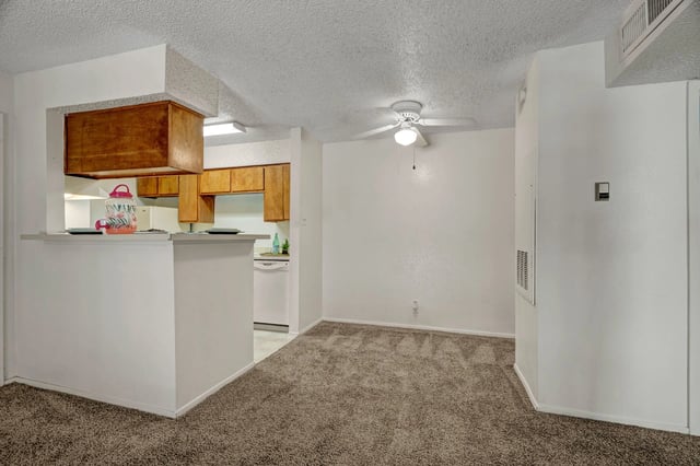 Living area and kitchen view with bar seating and appliances.