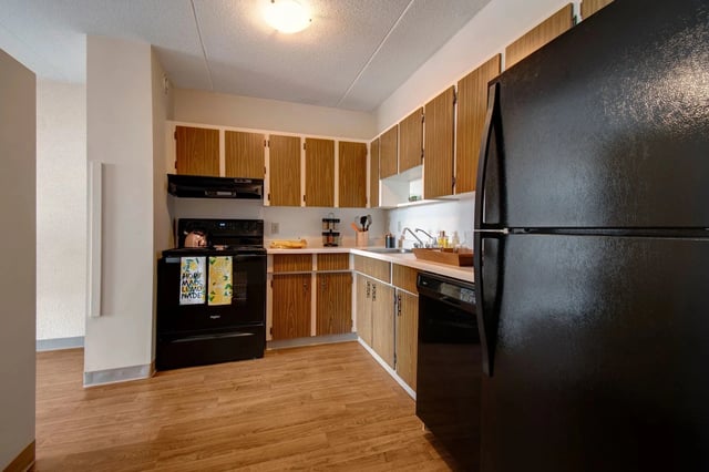 Kitchen with wooden cabinets, black appliances, and hardwood floors.