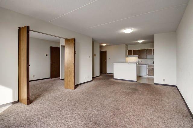 Living room and kitchen area with carpet flooring and bi-fold doors.