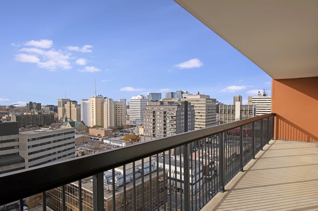 Balcony overlooking a city skyline with blue skies and clouds.